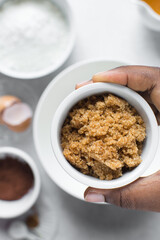 Brown sugar in a ramekin in a woman's hand, sugar for baking in a ramekin