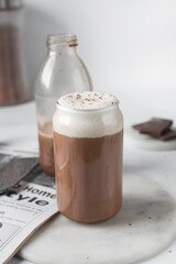 Mocha latte with whipped cream in a can shaped glass, iced mocha with foam on a table
