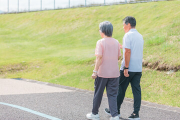 公園でウォーキング・有酸素運動する高齢者夫婦の後ろ姿（シニア・男女）

