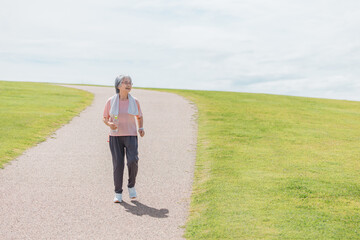 公園でウォーキング・有酸素運動・ランニングする高齢者女性
