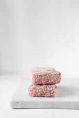 Pink lamingtons on a marble tray, Australian raspberry lamingtons, cake covered in desiccated coconuts