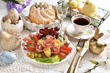 Easter table with a platter of ham and cheese appetizer and ring cake