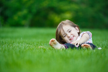 Naklejka na ściany i meble Happy child laying in perfectly manicured organic chemical-free green lawn grass