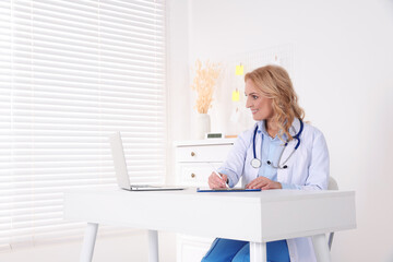 Doctor with laptop consulting patient in clinic. Online medicine concept