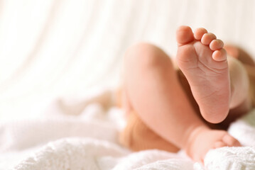 Obraz na płótnie Canvas Cute newborn baby lying on bed, closeup of legs. Space for text