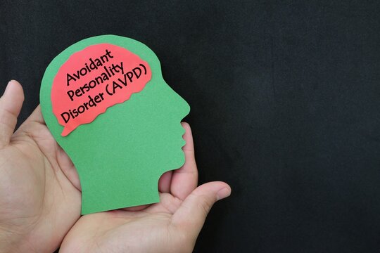 Avoidant personality disorder help, care and treatment concept. Hand holding human head profile with word text on brain on dark background.