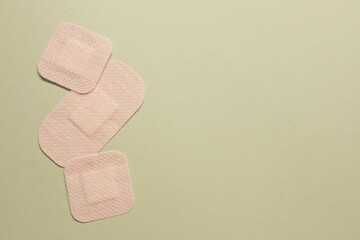 Different contraceptive patches on green background, flat lay. Space for text