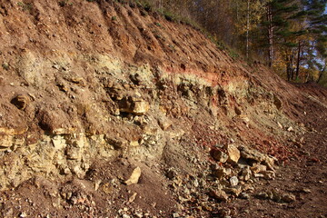 Part of the slope dug by an excavator with exposure of limestone rocks and clays of the Carboniferous period, lying under a layer of Quaternary deposits. Kaluzhskiy region, Russia