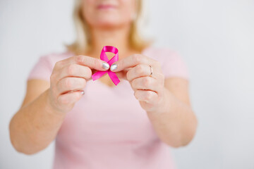 Woman in pink sweater with pink ribbon supporting breast cancer awareness campaign