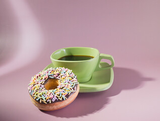 A stylish breakfast with a green cup of espresso black coffee and a sprinkle donut on a Pastel Background
