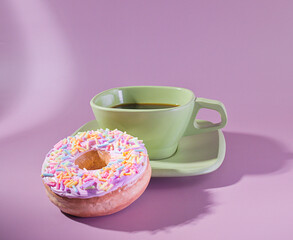 A stylish breakfast with a green cup of espresso black coffee and a sprinkle donut on a Pastel Background