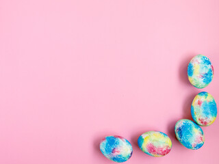 Fototapeta na wymiar Colorful handmade Easter eggs painted like Earth on pink paper background with copy space for Easter text message. Minimal happy Easter holiday conceprt. Top view flat lay, border frame in corner