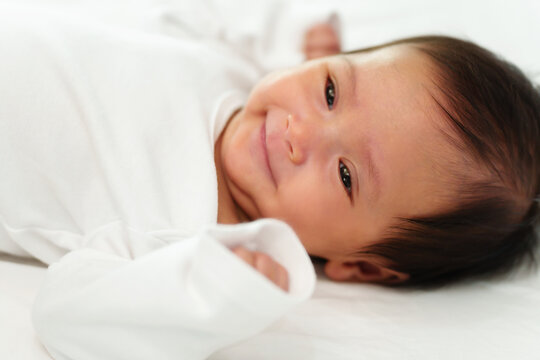 happy newborn baby smilling while lying on a bed