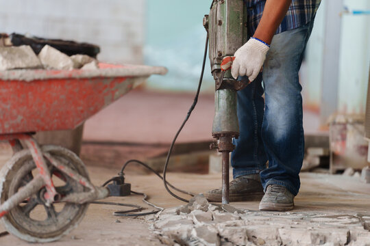 labor using a jackhammer to break up concrete floor