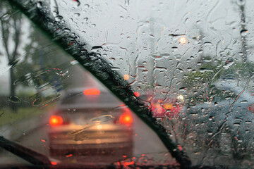 Windshield wipers from inside of car, season rain,filter color effect. Selective focus to rain droplet with motion blurry wiper - obrazy, fototapety, plakaty