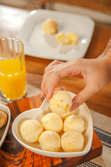 Female hand picking up a cheese bread. (Pao de queijo)