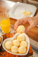 Female hand picking up a cheese bread. (Pao de queijo)