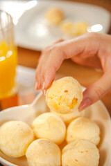 Female hand picking up a cheese bread. (Pao de queijo)