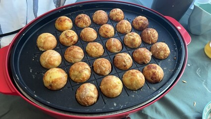 Takoyaki meatballs being baked in the electric grill
