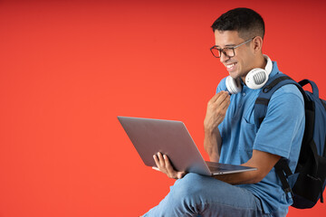 Young man with glasses and headphones, sitting cross-legged being happy and laughing while making a video call on a laptop