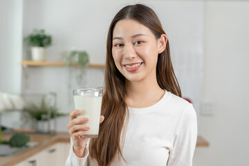 Health care, pretty asian young woman, girl drinking a glass of white fresh, dairy milk for calcium, vitamin wholesome good nutrition in morning at kitchen home. lifestyle, product healthy people.