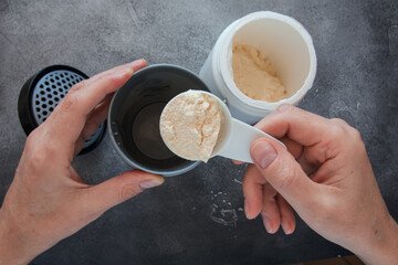 Top view of man adding protein powder to protein shaker bottle. Body care and healthy lifestyle...
