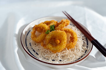 Close-up of fried vermicelli with sausages, prawns and vegetables on plate on table. Vertical top view from above