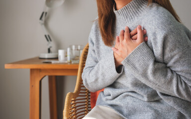 Closeup image of a woman with hands on chest, sudden heart attack, suffering from chest pain
