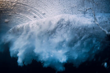 Barrel wave break in ocean with sunset or sunrise light. Underwater view of surfing wave