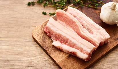 fresh raw streaky pork on wood board with ingredients and thyme leaves on wooden table background. raw streaky pork                       
