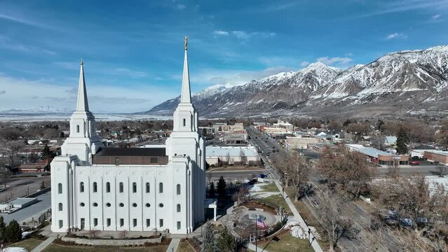 Aerial Brigham City Utah LDS Temple pan. The Church of Jesus Christ of Latter-day Saints, LDS or Mormon Church. Spiritual sacred church. Urban neighborhood in mountain valley. Winter snow.