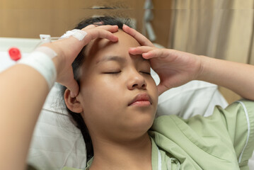Asian woman patient with medical drip have headache with migraine headaches hospital ward, teenager sick in hospital with saline intravenous, Selective focus, healthcare and health insurance concept.