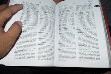 Closeup hand of Asian people open and read dictionary book at library. person reading a book on the table