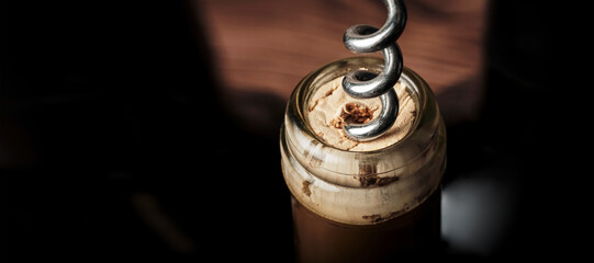 a corkscrew is screwed into a wine cork, close-up, copy space