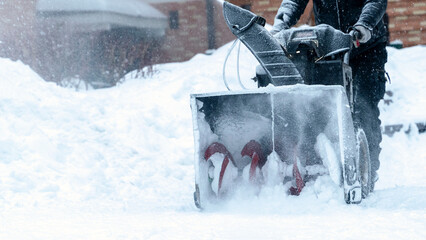 a janitor on a snowplow removes snow in the courtyard of a residential building