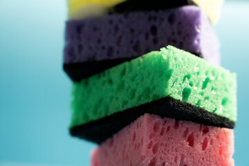 Multicolored sponges for washing dishes and other household needs. The sponges lie on a blue background at a slight angle. Cleaning and Dishwashing Concept