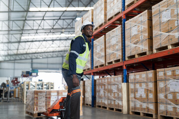 Naklejka na ściany i meble African American male warehouse worker pushing load cart at the storage warehouse. Male warehouse worker moving boxes of products at distribution branch .Inspection quality control