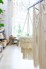 Macrame store with bohemian curtain on big window, lampshade and boho baskets