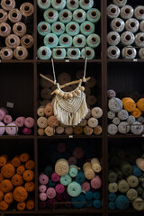 Macrame shop with full shelves of multicolored cotton balls of yarn and ropes with hanging macrame decor