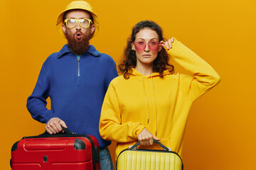 Woman and man smiling, suitcases in hand with yellow and red suitcase smiling merrily and crooked, yellow background, going on a trip, family vacation trip, newlyweds.