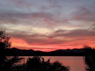 Sunset River View. Sunset sky. Vibrant beauty from sunset pictured with silhouette of mountain and trees.