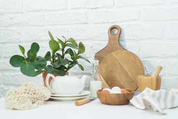 Home kitchen interior with easter decor. Blooming flower in a pot, eggs in wooden pot, wooden planks, milk in a bottle on a light background