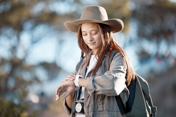 Woman, tourist and checking watch in hiking, adventure or backpacking journey in the nature outdoors. Female hiker looking at wristwatch for travel, time or mountain trekking in performance check