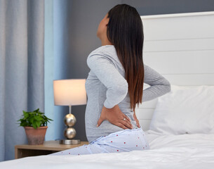 Tired, burnout and pregnant woman with back pain on a bed for rest, injury and fatigue. Healthcare,...