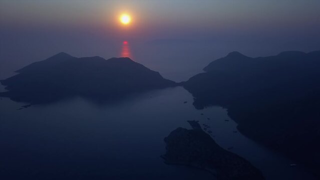 Ethereal deep blue and orange ocean sunset aerial: dark dusk islands