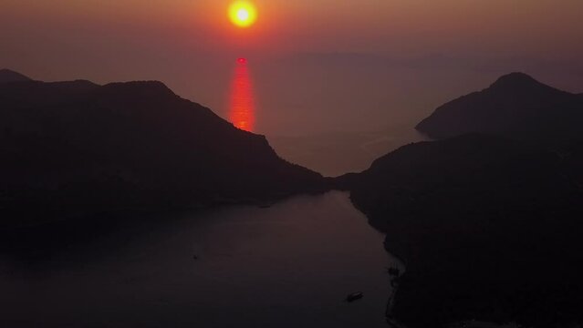 Golden aerial view: Orange ocean sunset behind mountainous islands