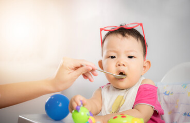 Fototapeta na wymiar Asia baby boy child sitting eating food on chair at home