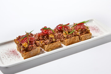 Aesthetic composition with shredded beef bruschetta on white background over white wall. Italian bruschetta with shredded beef and mustard on fine dining in summer. Elegant menu concept.