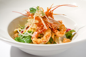 Elegant food - salad with shrimp and avocado on white table with harsh shadow. Flashy food concept. Seafood salad with shrimp, tomatoes and avocado on white plate with sunlight.