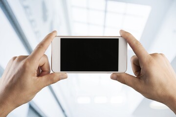 Hand holding mobile phone with a black screen.